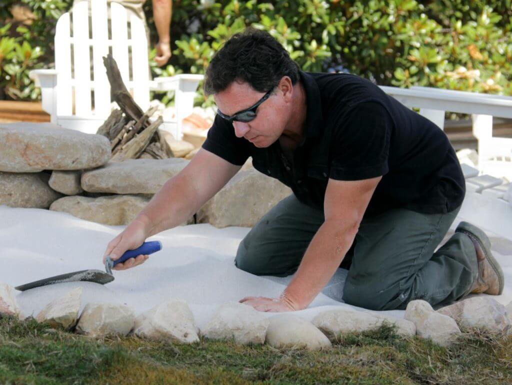 Guy making a sand fire pit